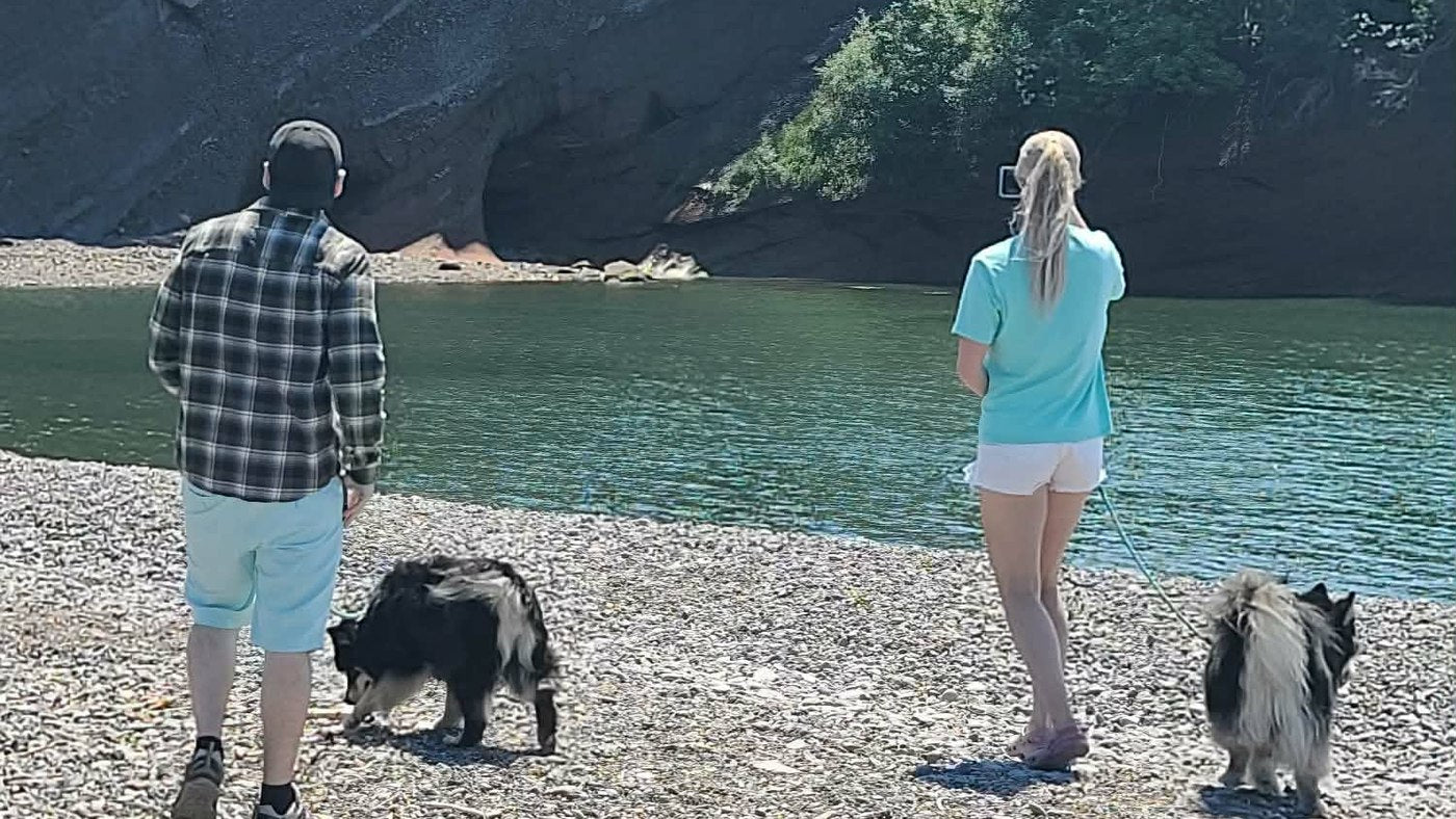 Both of us and both dogs standing on the gravel at the edge of a cove