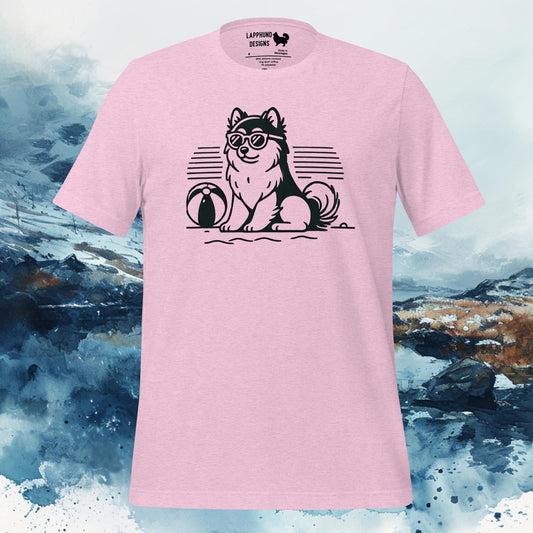 Pink t-shirt featuring a Finnish Lapphund wearing sunglasses with a beach ball, sitting on the sand, against a stylized sunset background, perfect for summer-loving dog owners.