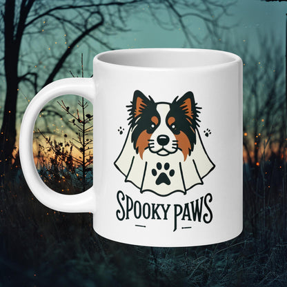 White ceramic mug featuring a Finnish Lapphund dressed as a ghost with the text 'Spooky Paws,' perfect for Halloween and dog lovers.